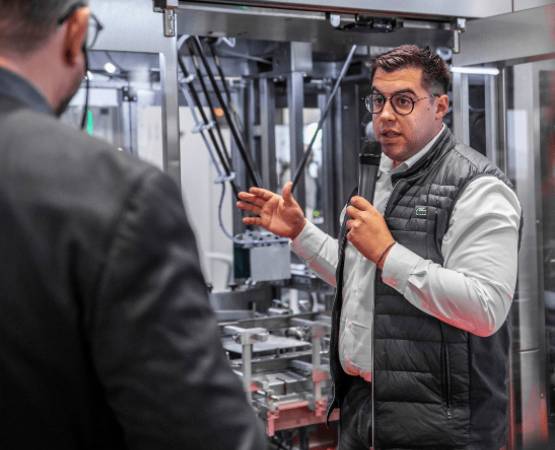 a man speaking into a microphone in front of a machine