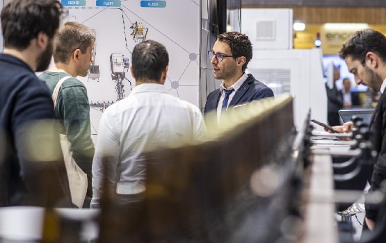 Un exposant présentant son innovation à plusieurs visiteurs.