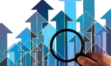 Main tenant une loupe devant des flèches bleues pointant vers le haut, symbolisant la croissance ou l’analyse de tendances en hausse.