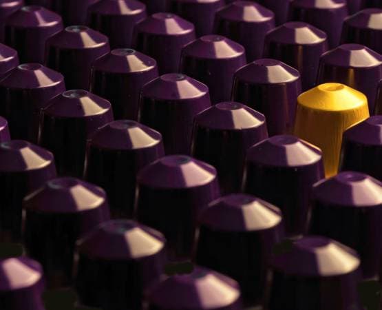 rows of purple coffee capsules, including one yellow one