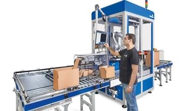 machine pour l'emballage : un carton est posé sur un tapis roulant devant laquelle se trouve un homme 