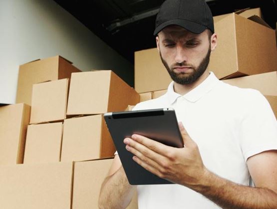 A logistics worker checking packages using a tablet in a delivery vehicle
