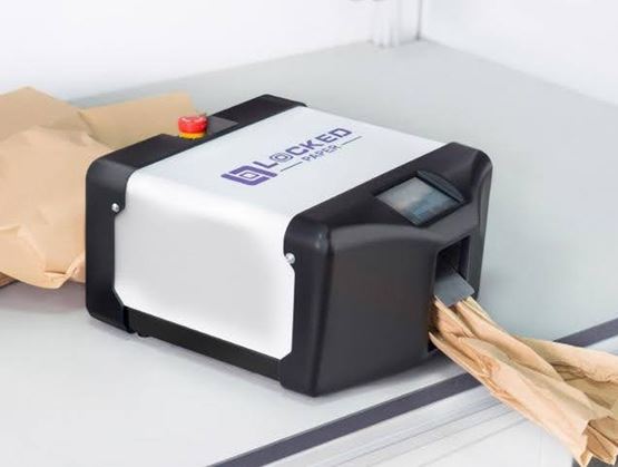 Machine compacte Locked Paper posée sur une table, avec écran de contrôle et bouton d’arrêt d’urgence, produisant du papier de calage froissé pour l’emballage.