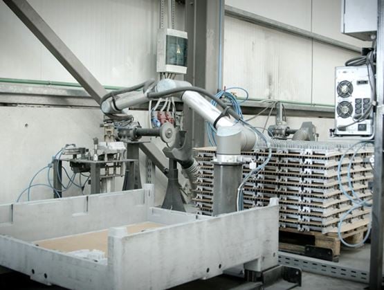 Bras robotisé industriel manipulant des plateaux empilés dans une ligne de production automatisée au sein d’un atelier de fabrication.