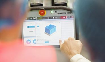 Opérateur utilisant une tablette pour programmer un robot collaboratif Universal Robots via une interface de modélisation 3D affichant un objet sur l’écran.