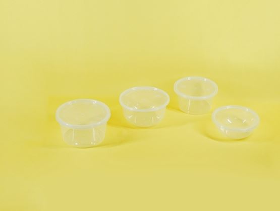 Four small transparent plastic food containers with lids arranged on a plain yellow background.