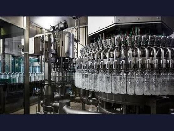 Ligne industrielle d’embouteillage avec des bouteilles en plastique transparent.