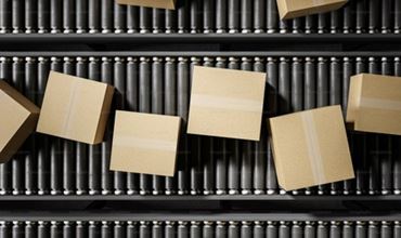 Cardboard packages moving on roller conveyors in an automated logistics center.