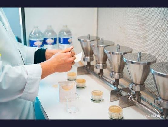 Laboratory handling for filling small jars with a cosmetic or food preparation.