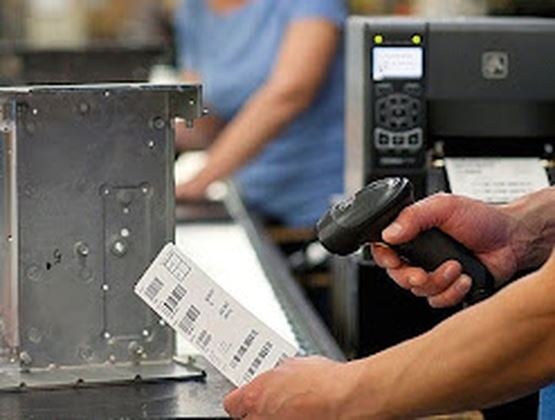 Operator scanning a barcode label next to an industrial metal component.