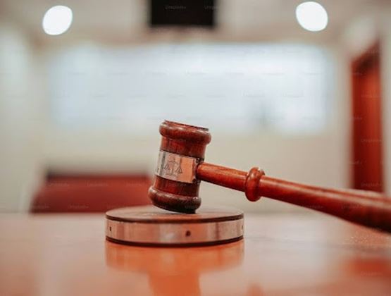 Maillet de juge en bois posé sur son socle dans une salle d’audience floue.