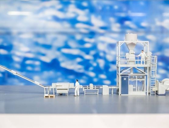 Model of an industrial production line displayed in a showcase at a trade show.