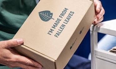 Person holding a cardboard box of madeleines at a trade show.