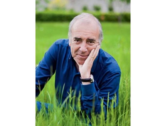 Portrait d’un homme en chemise bleue allongé dans l’herbe, la main posée sur le visage.