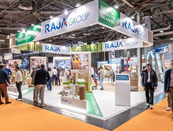 RAJA Group booth at a trade show, showcasing packaging solutions in front of several visitors.