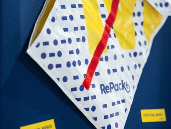 Sac réutilisable RePack accroché sur un mur bleu lors d’un salon professionnel.