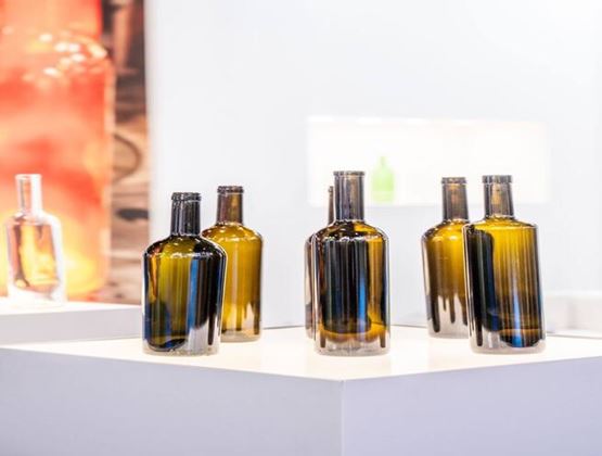 Collection of amber glass bottles displayed on white plinths at an exhibition.