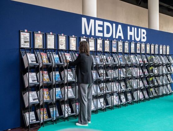 Visitor browsing magazines and professional publications in the Media Hub area of a trade show.
