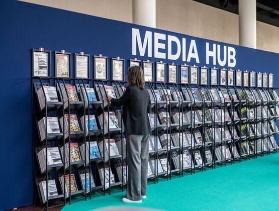 Visiteuse consultant des magazines et documents professionnels dans l’espace Media Hub d’un salon.