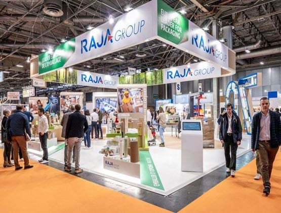 Stand RAJA Group sur un salon professionnel de l’emballage, avec visiteurs, signalétique suspendue et solutions exposées.