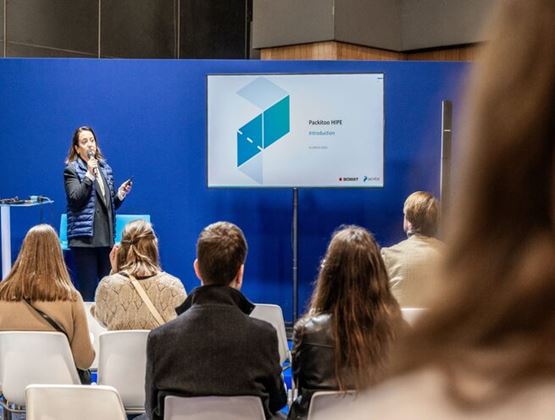 Professional packaging conference with a speaker presenting the Packito HIPE solution to a seated audience.