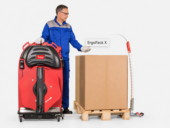 Operator using an ErgoPack strapping system beside a palletised cardboard box.