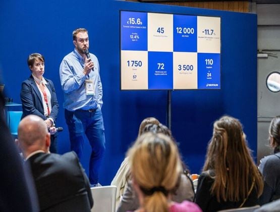 Speakers presenting industry figures to an audience during a conference session.