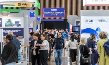 Des visiteurs circulent dans les allées de NRF Europe près de la scène Breakout Sessions et des stands technologiques.