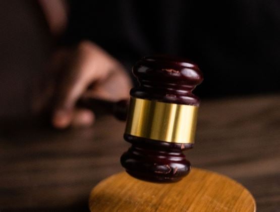Marteau de juge au-dessus d’un socle en bois dans un environnement judiciaire.