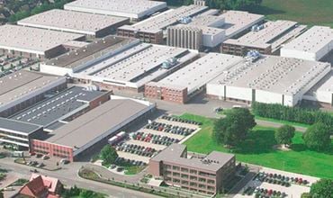 Aerial view of a large industrial production site with factory buildings and surrounding green areas.