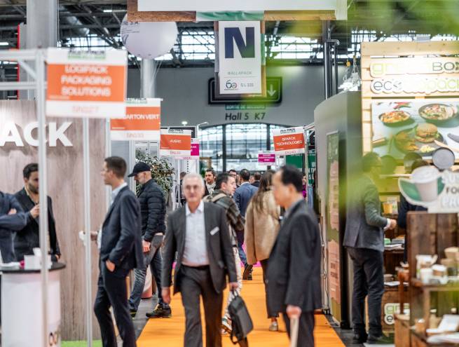 aisle of a trade fair surrounded by stands and people