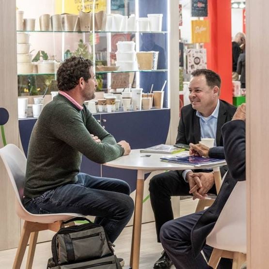 Deux visiteurs observent une vitrine présentant différents emballages et contenants innovants sur un salon.